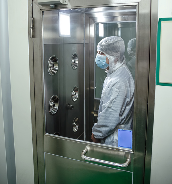 lab worker dressed in PPE gear standing inside a sanitization room 