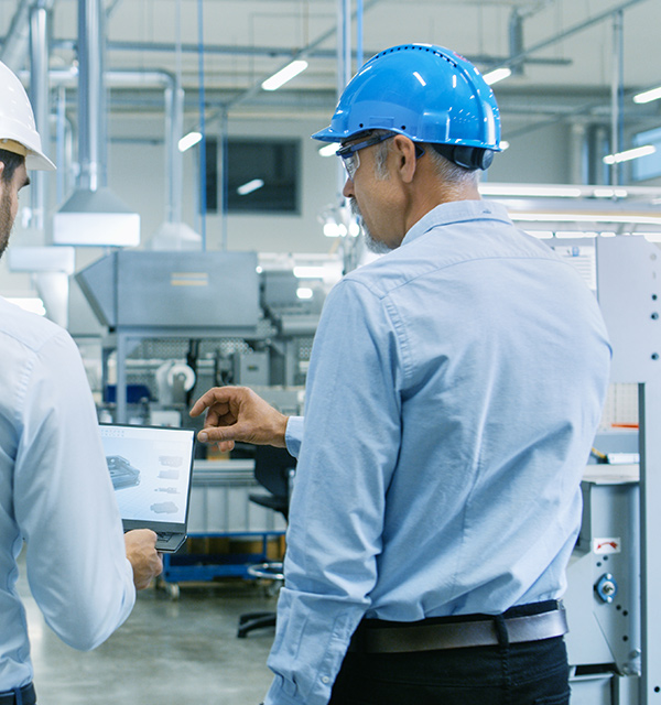 cleanetics engineers wearing hardhats and discussing plans over a laptop